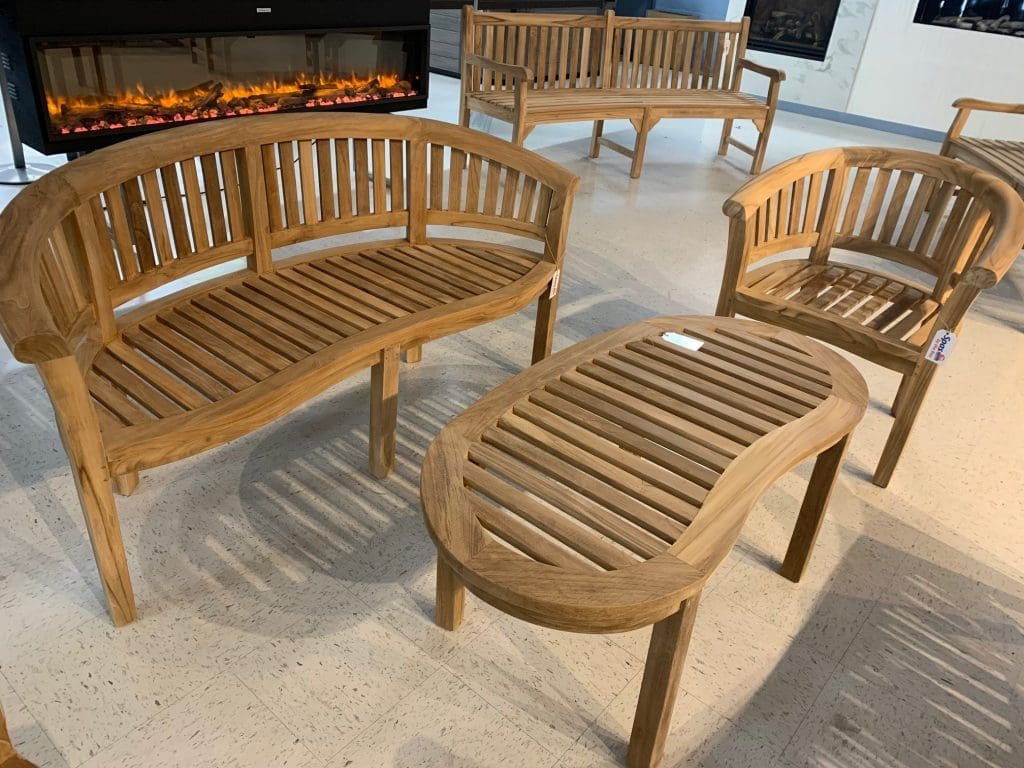 teak patio furniture in a showroom - a patio bench, patio chair and patio table