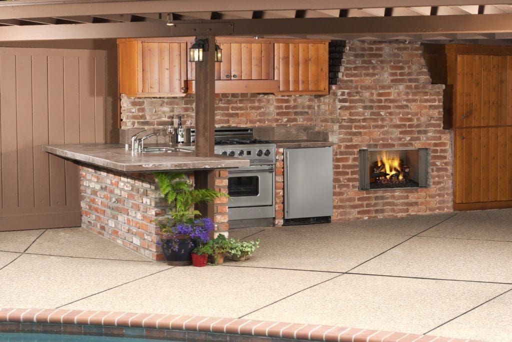 Outdoor living example - fireplace built into the outside wall of a house next to an outdoor kitchen setup