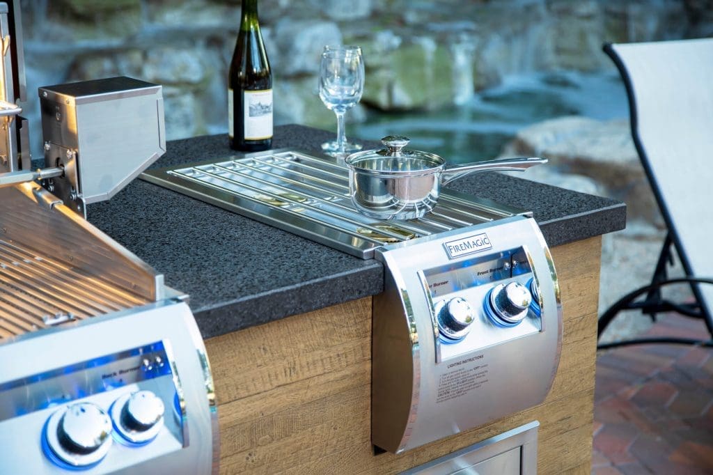 Outdoor kitchen close-up with a wine bottle, wine glass, and pot resting on top