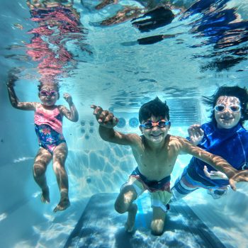 Three kids underwater in a swim spa
